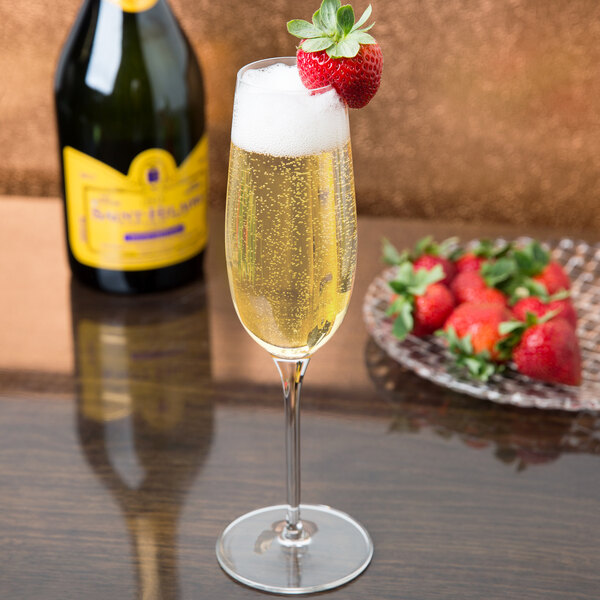 A Reserve by Libbey champagne flute filled with champagne with a strawberry on the rim.