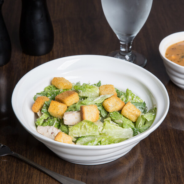 A bowl of salad with chicken, croutons, and a fork.