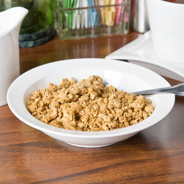 A bowl of cereal with a spoon in a white Arcoroc porcelain bowl.