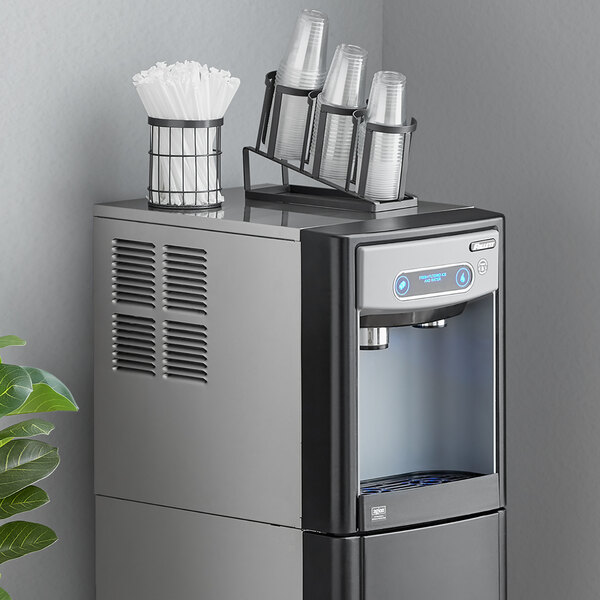 A Follett countertop ice maker and water dispenser with a cup holder on top.