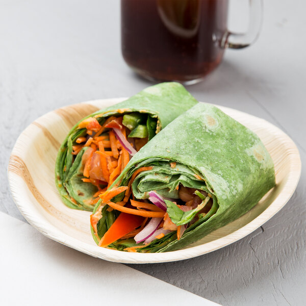 A table with a EcoChoice palm leaf plate holding a salad, vegetables, and a drink.