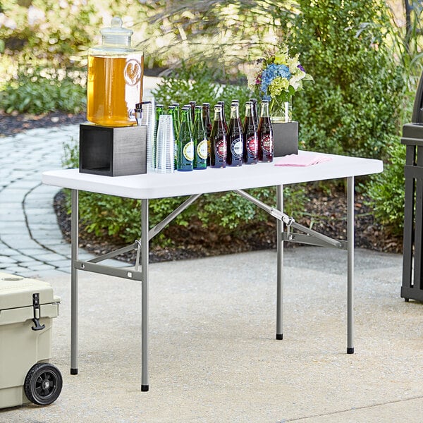 A Lancaster Table & Seating heavy-duty folding table with bottles of soda on it.
