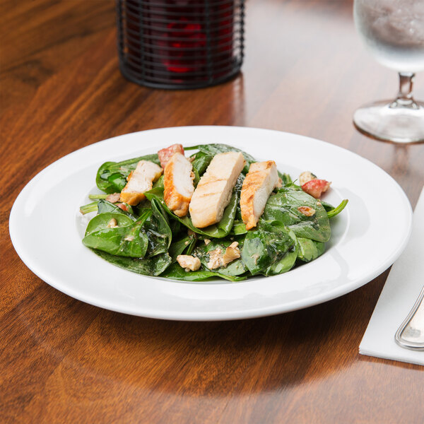 A plate of salad with chicken and spinach on an Arcoroc brunch plate.