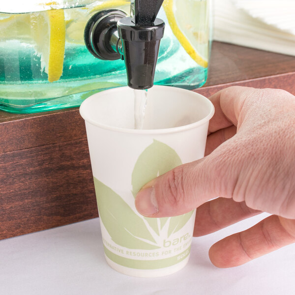 A person pouring water into a Bare by Solo paper cold cup.