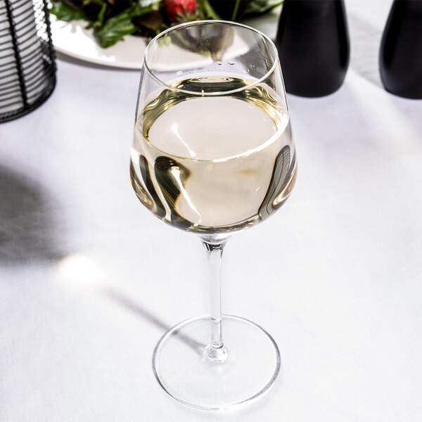 A Reserve by Libbey wine glass filled with white wine on a table.