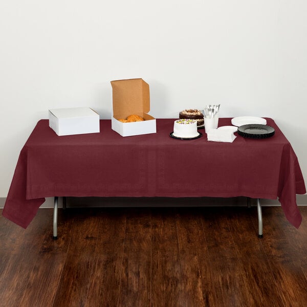 A table with Creative Converting Burgundy Tissue/Poly Table Cover on it with food.