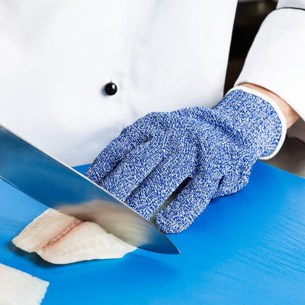 A person wearing San Jamar blue cut resistant gloves cutting fish.