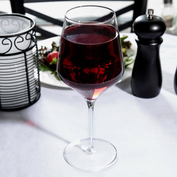 A close-up of a Reserve by Libbey Prism wine glass filled with red wine on a table.