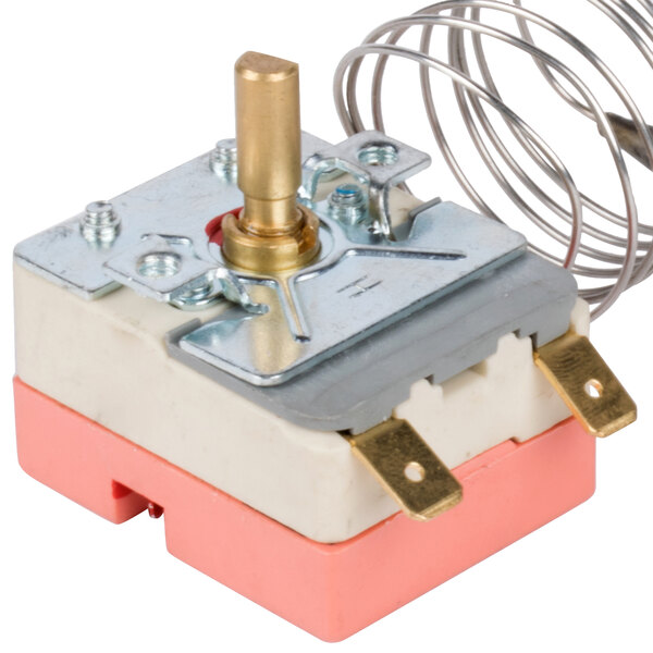 A close-up of a small metal thermostat with wires attached.