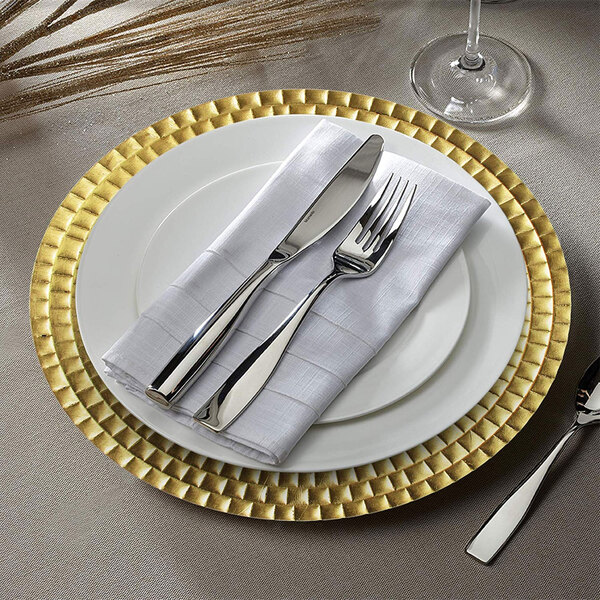A gold Charge It by Jay plastic charger plate with silverware and a napkin on it.