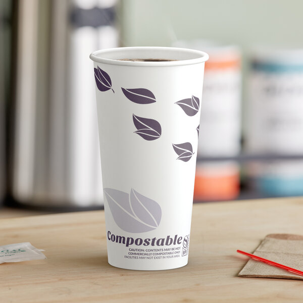 A close-up of a white EcoChoice paper hot cup with purple leaf designs on a table.