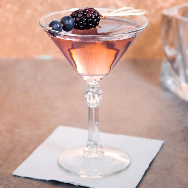 A Libbey martini glass filled with pink liquid and garnished with blackberries.