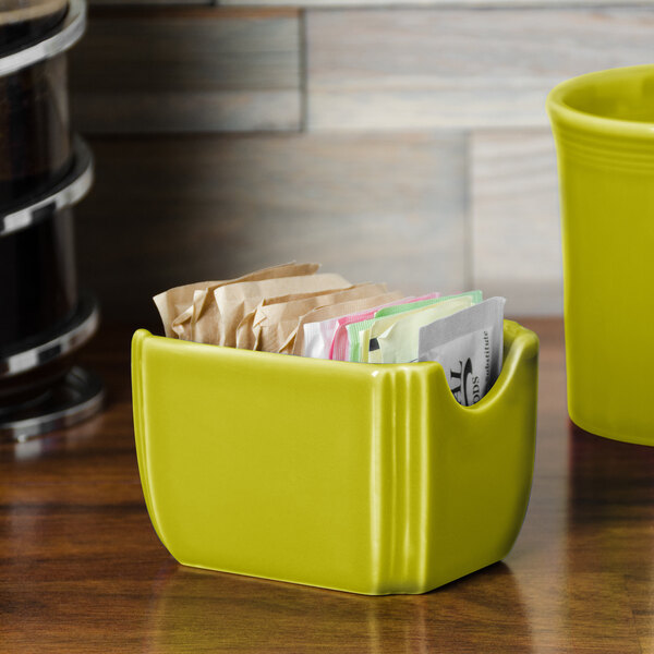A lemongrass yellow Fiesta sugar caddy holding packets on a counter.