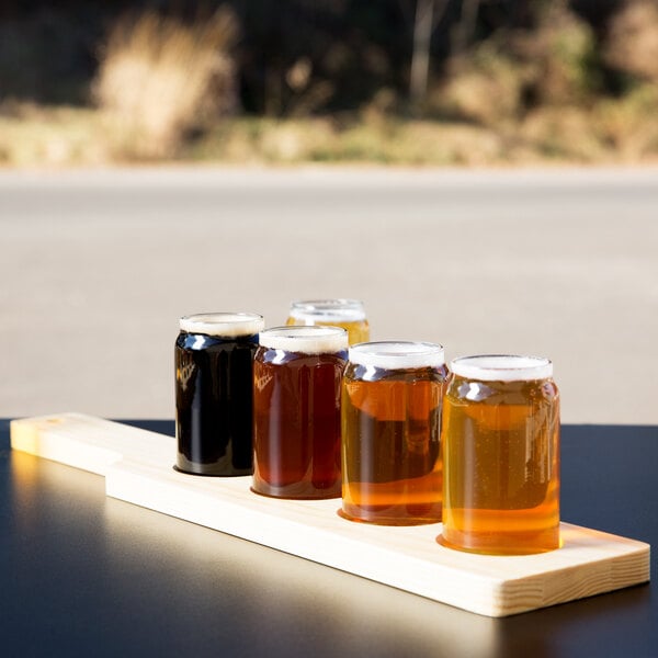 A row of Libbey Mini Can Tasting Glasses on a natural flight paddle.