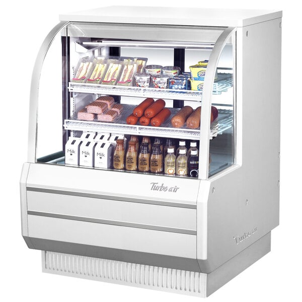 A Turbo Air white refrigerated deli case with food displayed inside.