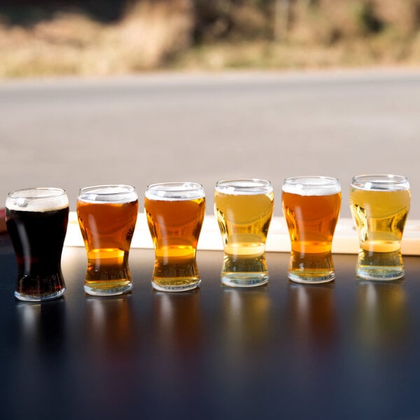 A row of Libbey Mini Pub Beer Tasting Glasses filled with beer on a table.
