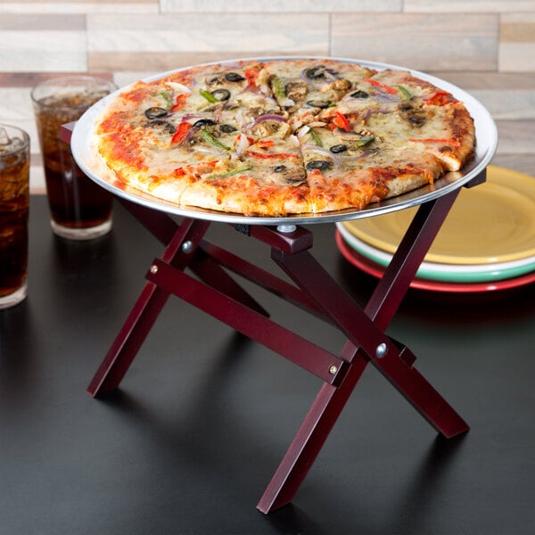 A pizza on a Tablecraft mini tray stand on a table.