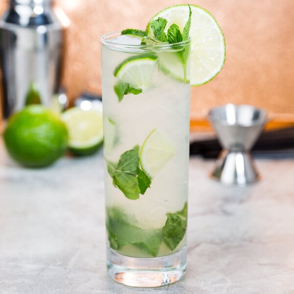 An Acopa mojito glass filled with a drink and lime slices.