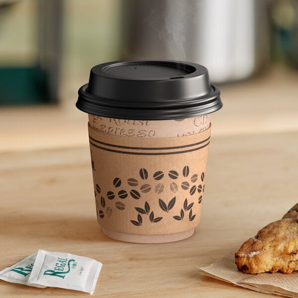 A Choice coffee cup with a Kraft sleeve and black lid on a table with a cookie.