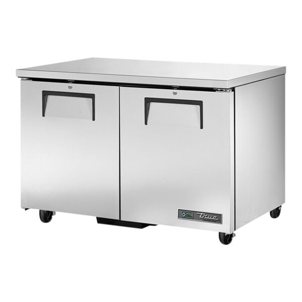 A close-up of a silver True low profile undercounter refrigerator on wheels.