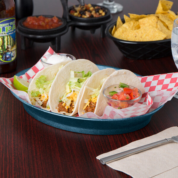 A blue HS Inc. oval deli server filled with a group of tacos with meat and lettuce on a table.