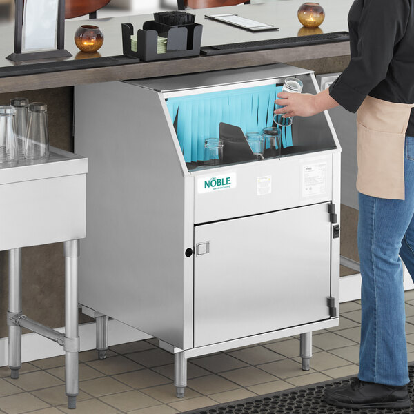 A stainless steel underbar glass washer with a carousel mechanism, shown in use at a commercial bar.