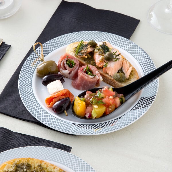 A white Visions plastic plate with food and a knife on a table.