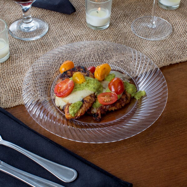 A Visions clear plastic plate of food with a fork and knife.