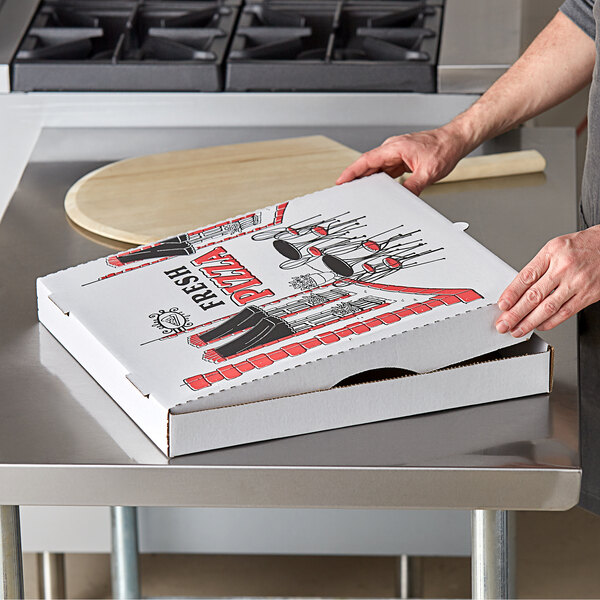 A person holding a Choice white corrugated pizza box on a counter.