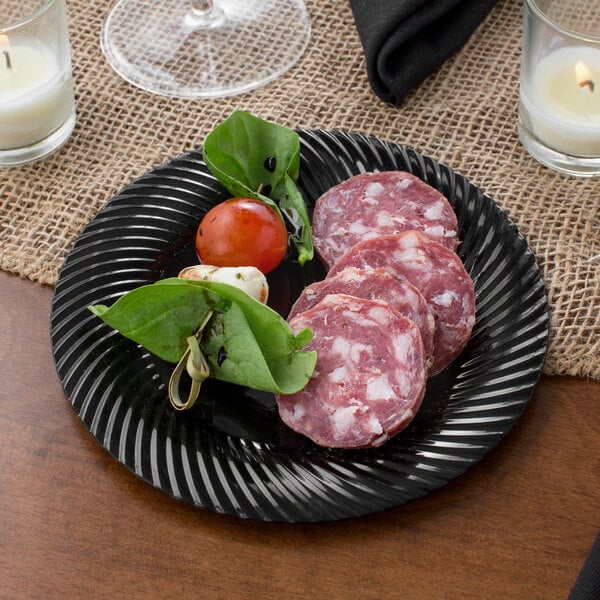 A Visions black plastic plate with meat and vegetables on it on a table.