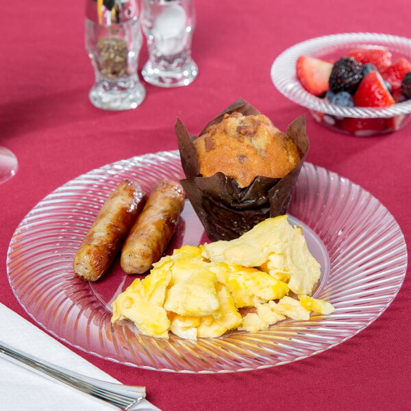 A Visions clear plastic plate with breakfast food and fruit on a table.