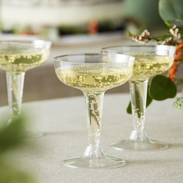 Visions clear plastic champagne glasses filled with champagne on a table in a catering event.