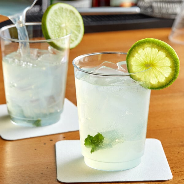 Two Choice clear plastic tumblers filled with ice water, lime slices, and mint leaves.
