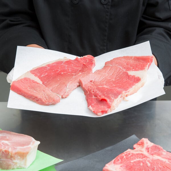 A person placing raw meat on white butcher paper.