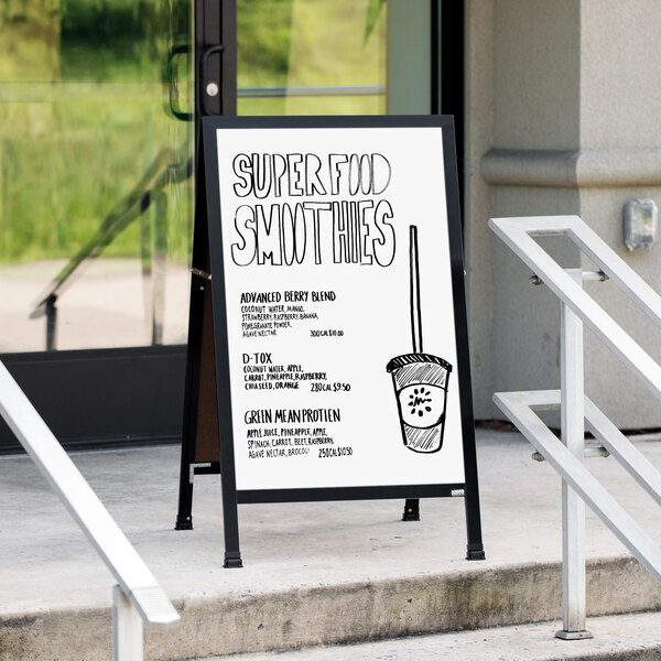 An Aarco black aluminum A-frame sign with a white marker board displaying a black and white circular drawing outside a restaurant.