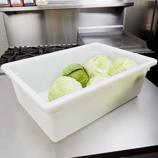 A white Carlisle food storage box filled with cabbages on a kitchen counter.