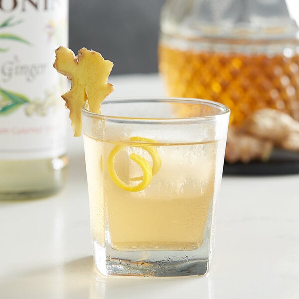 A glass of Monin ginger flavored liquid with a lemon twist.