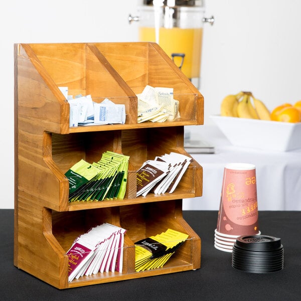 A Cal-Mil Madera rustic pine condiment display with clear bins holding packets on a wooden shelf.
