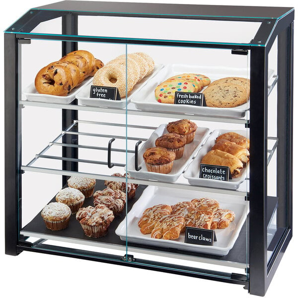 A black Cal-Mil bakery display case on a counter filled with bagels, cookies, muffins, and pastries.