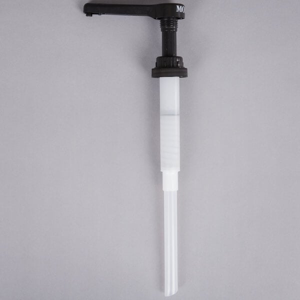 A white and black Monin puree pump with a black pipe and white plastic tube.