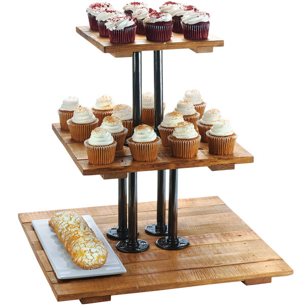 A wooden Cal-Mil Madera display riser holding cupcakes on a table.