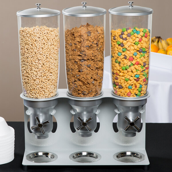 A Cal-Mil triple cereal dispenser on a table filled with three types of cereal.