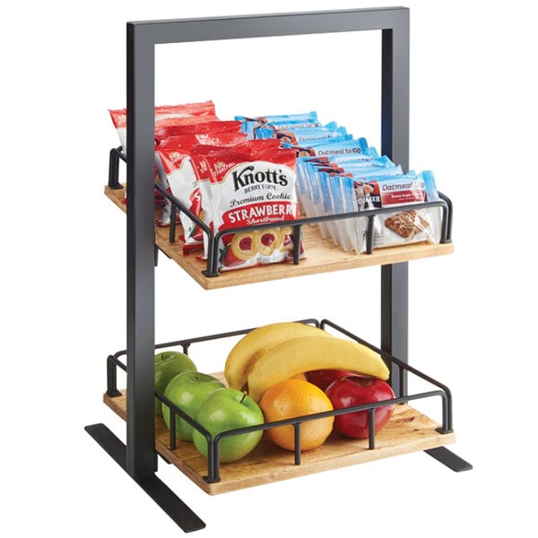 A Cal-Mil Madera two tier merchandiser shelf with fruit and snacks including bananas and oranges.