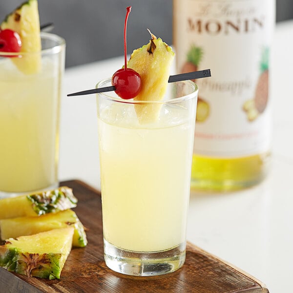 A glass of Monin pineapple juice with a cherry on top.