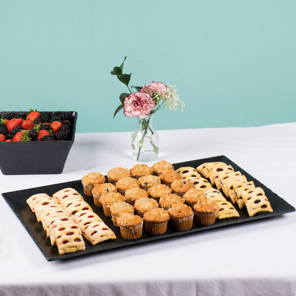 A Cal-Mil rectangular melamine platter with pastries, muffins, and fruit on a table.