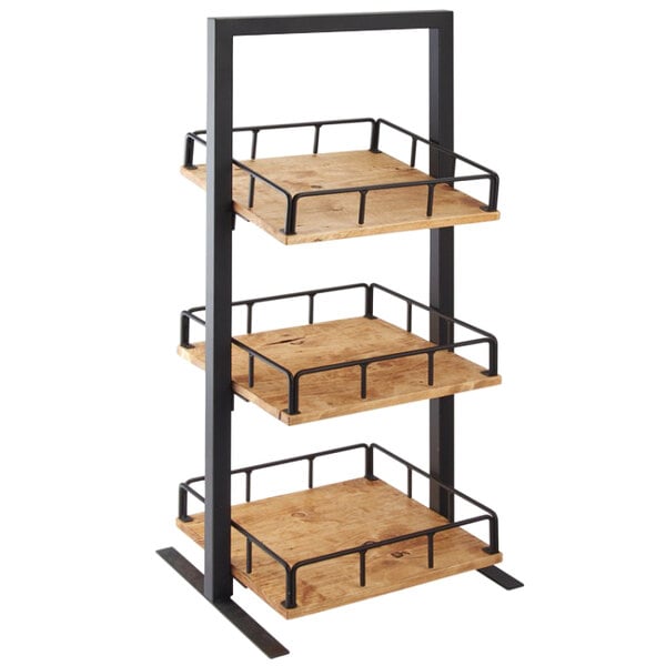 A wooden table with black metal bars holding a Cal-Mil Madera three tier merchandiser with baskets.