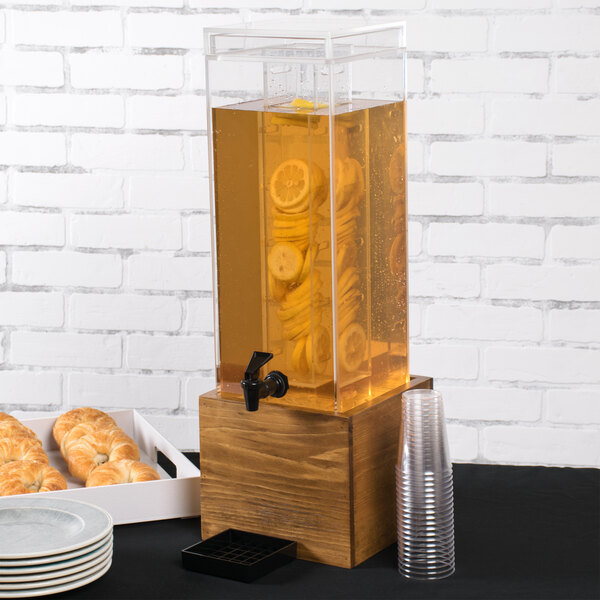 A Cal-Mil rustic pine beverage dispenser with an infusion chamber on a counter.