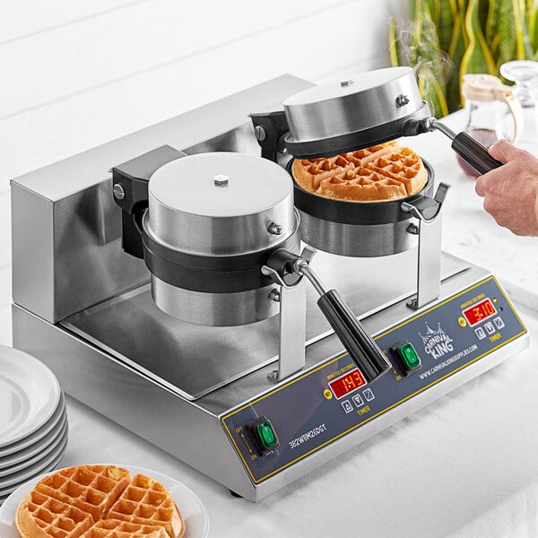 A person using a Carnival King double Belgian waffle maker to make waffles on a table in a breakfast diner.