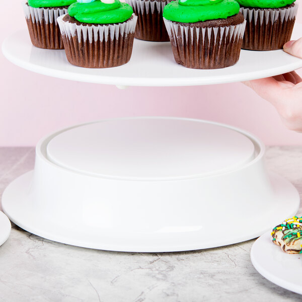 A person holding a plate with cupcakes on a white Elite Global Solutions melamine pedestal.