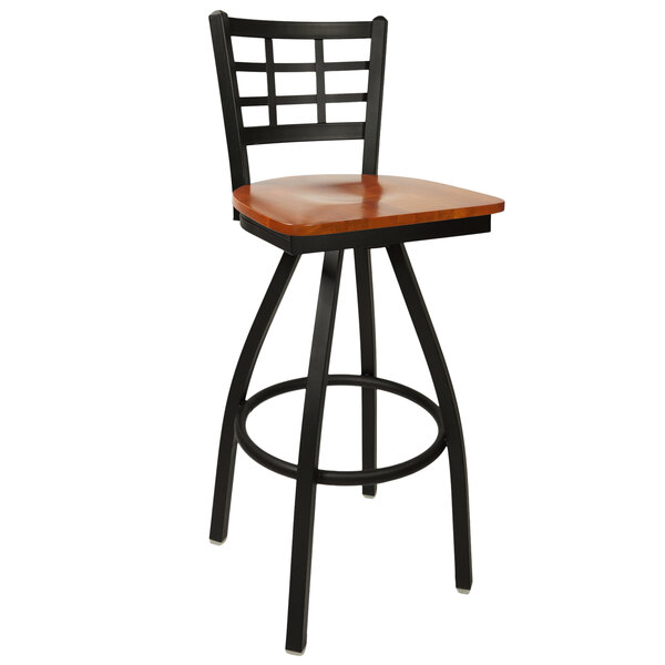 A BFM Seating black metal swivel bar stool with a cherry wood seat.